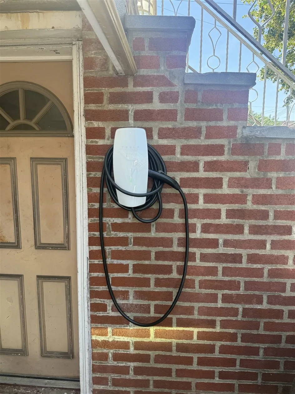 Tesla EV charger installed on brick building exterior by AE Electric NYC