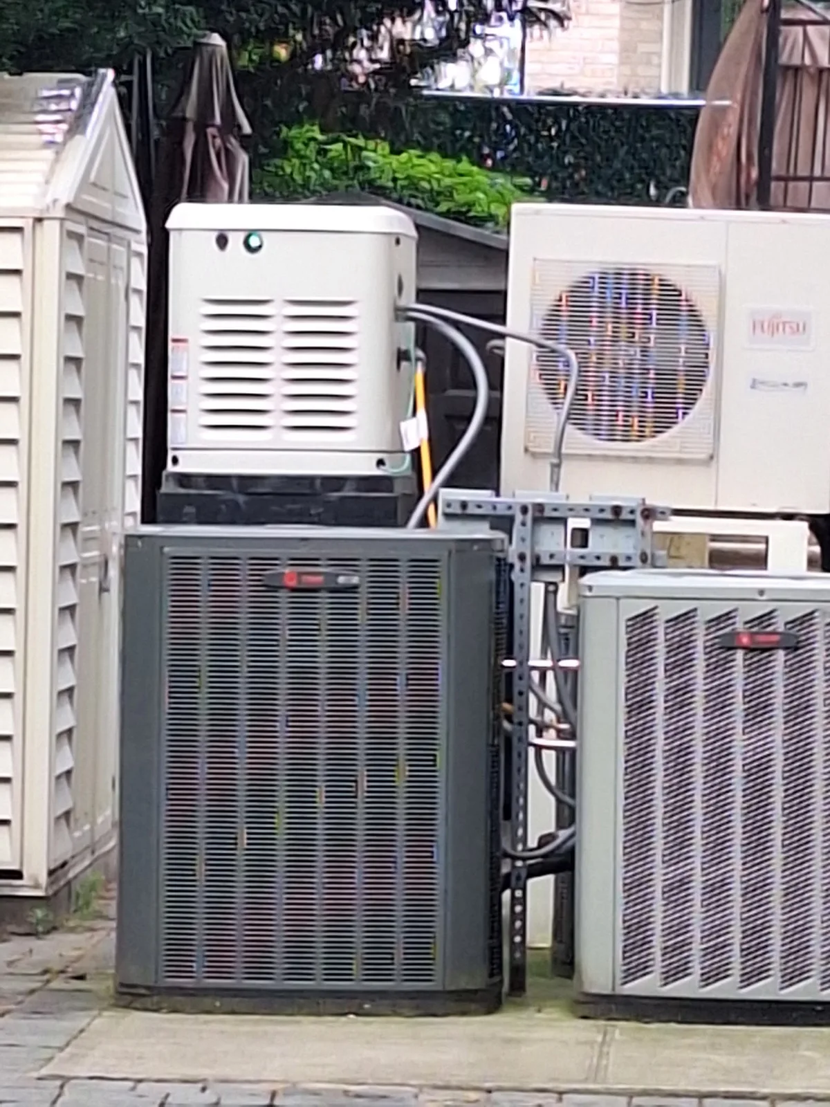 Whole-house standby generator installed in a Brooklyn, NYC backyard next to HVAC condensers by AE Electric