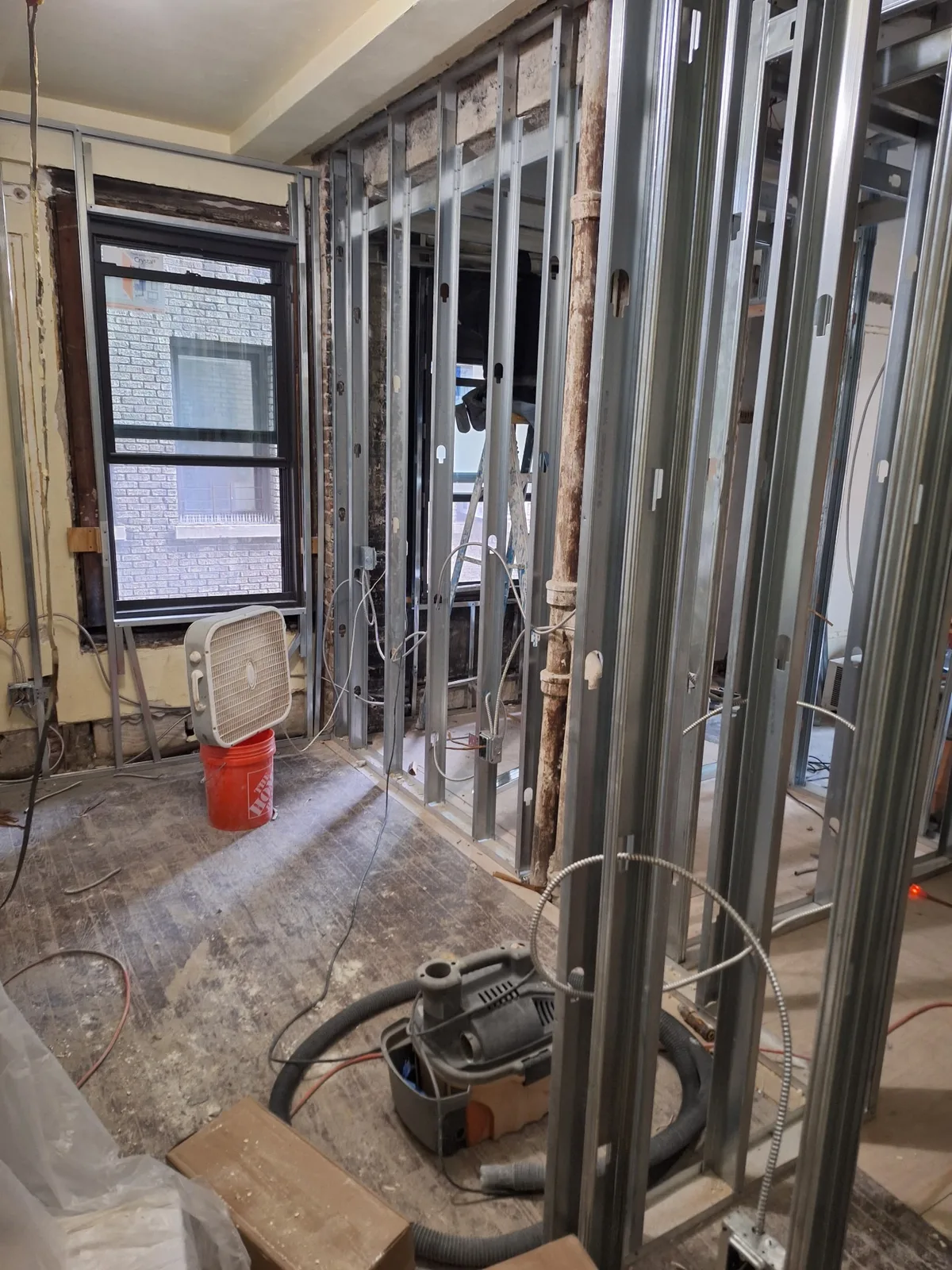 Walls opened to the studs during a full rewire of a Brooklyn house, with the old wiring removed and new BX cable run to fresh boxes