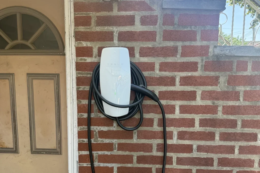 Level 2 EV charger mounted on the brick exterior of a private NYC house, fed by a dedicated 240-volt circuit installed by AE Electric